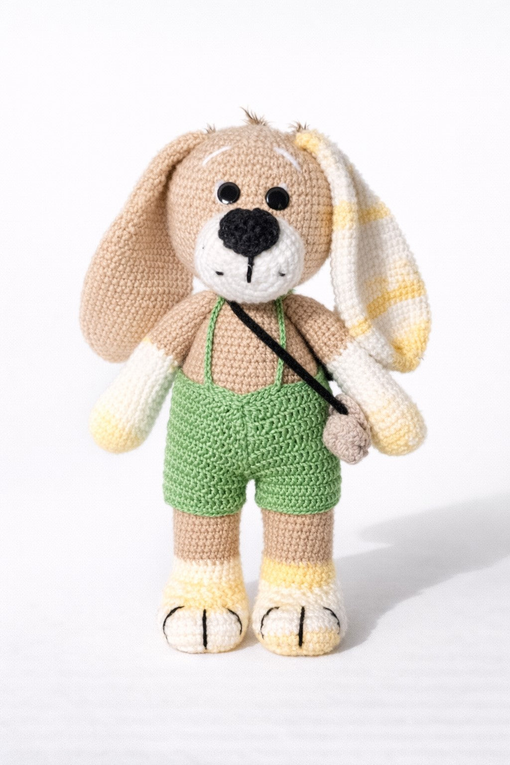 Crocheted bunny  with green overalls on a white background