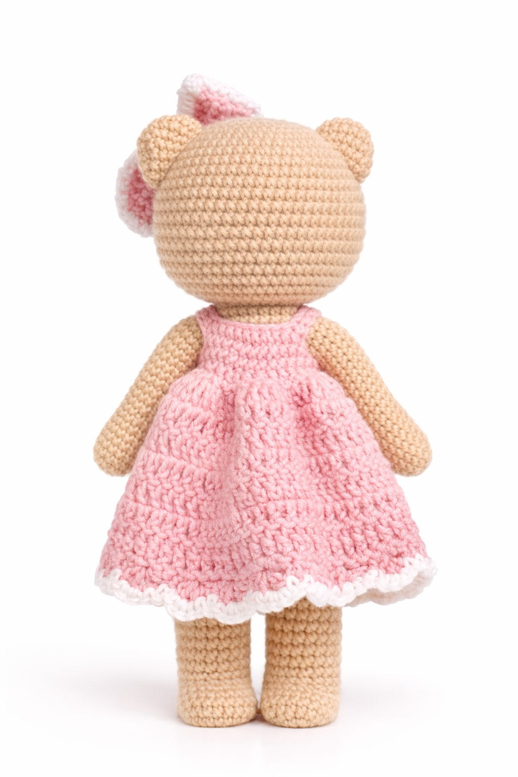 Crocheted teddy bear with a pink dress on a white background