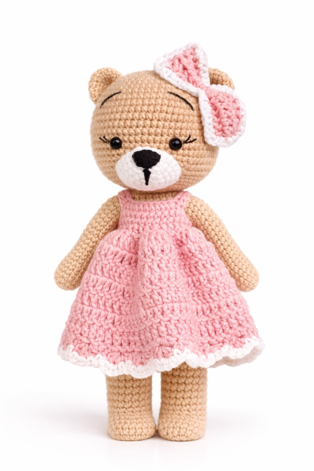 Crocheted teddy bear in a pink dress with a matching headband on a white background