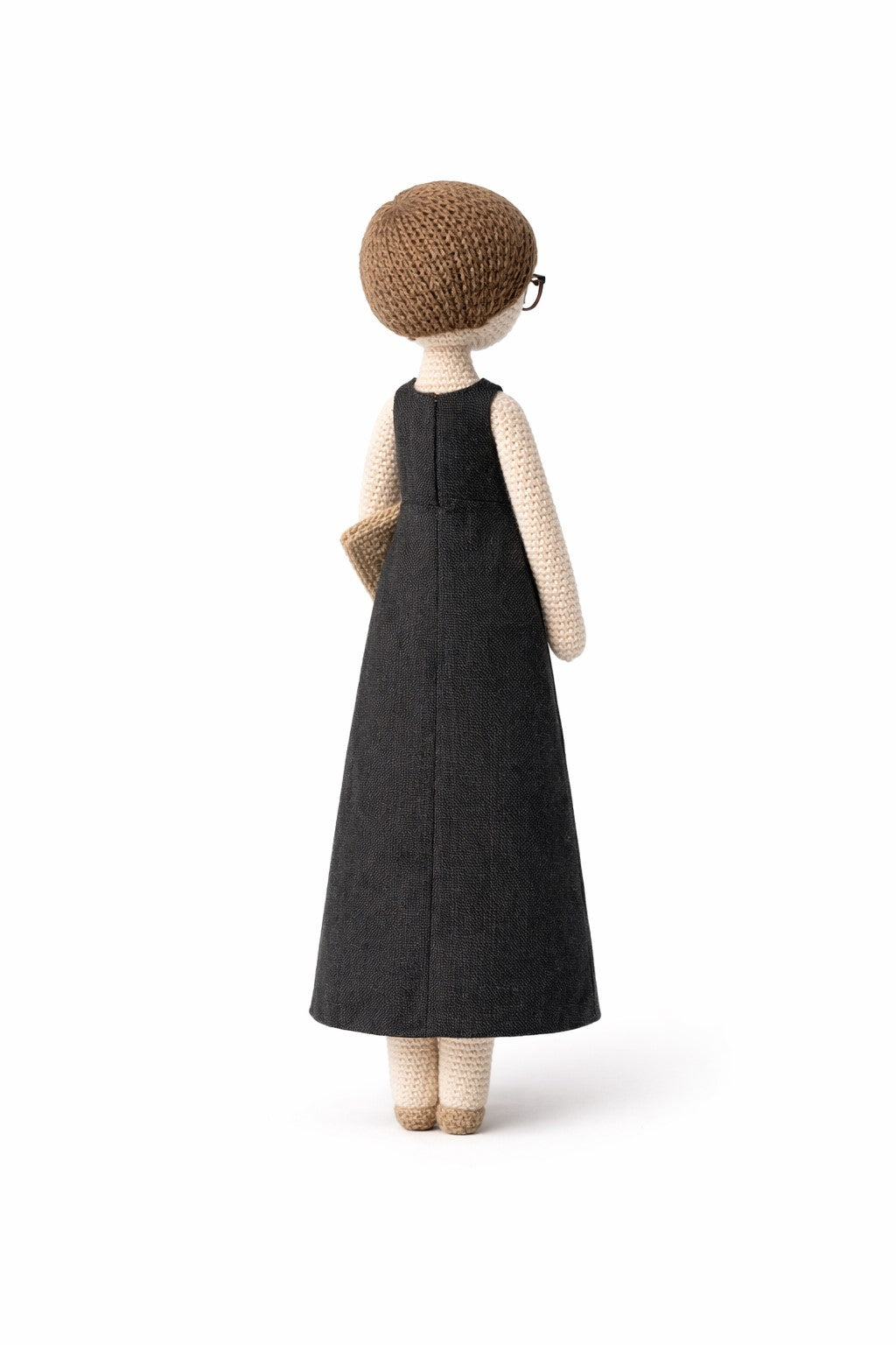 Textile doll with a black dress and knitted hat on a white background