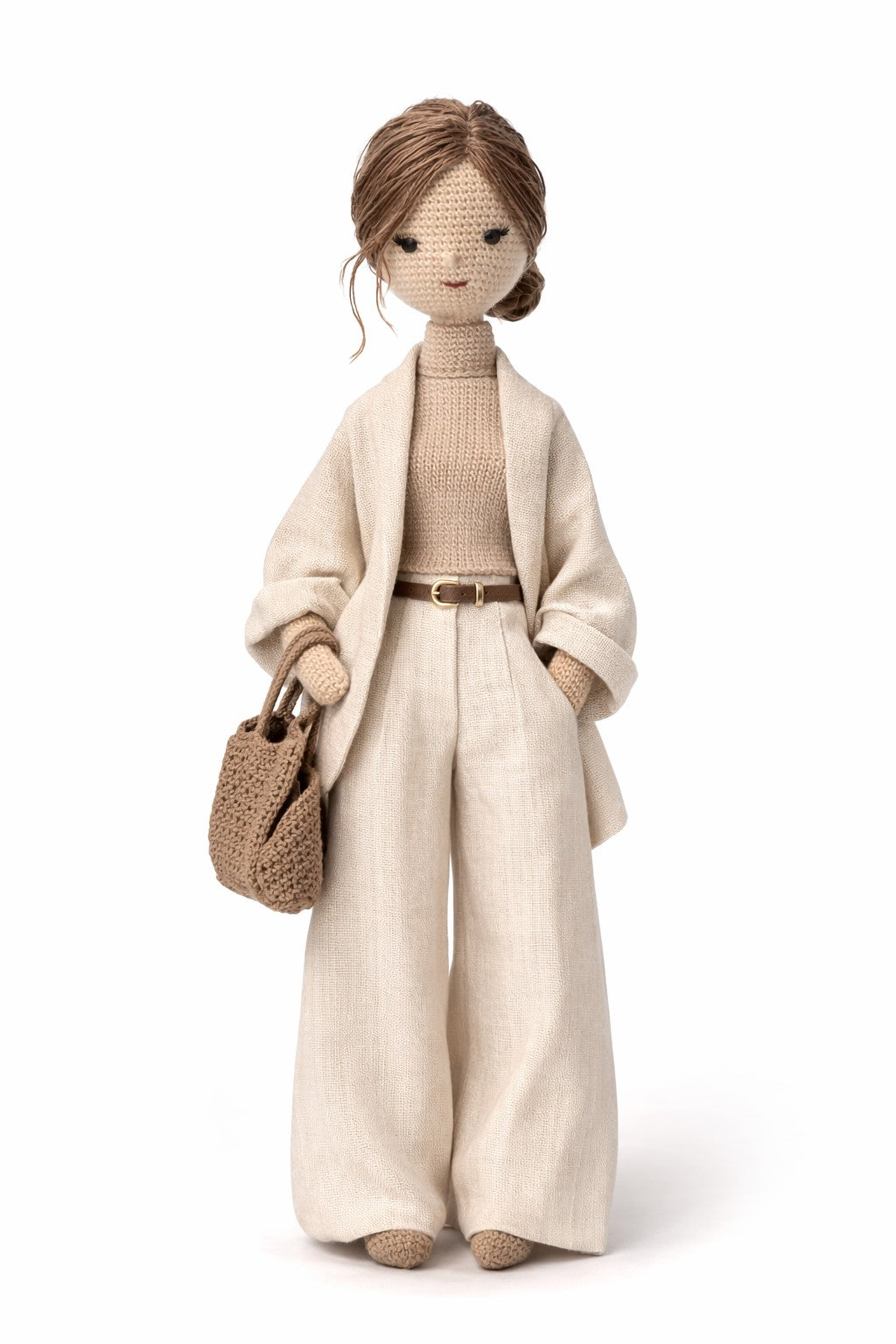 Crocheted figure wearing a beige outfit with a handbag on a white background